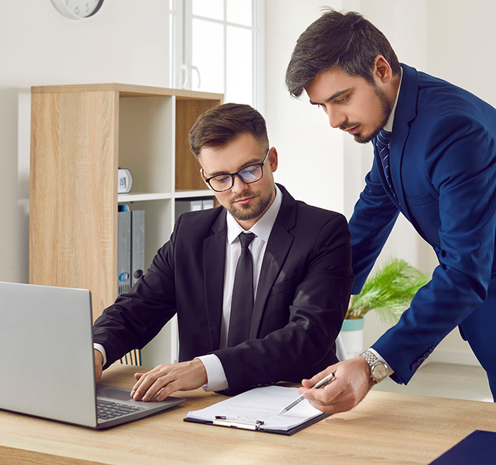 Two people looking at clipboard and laptop
